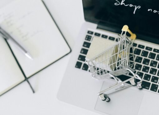 Creative depiction of online shopping with a miniature cart on a laptop keyboard.